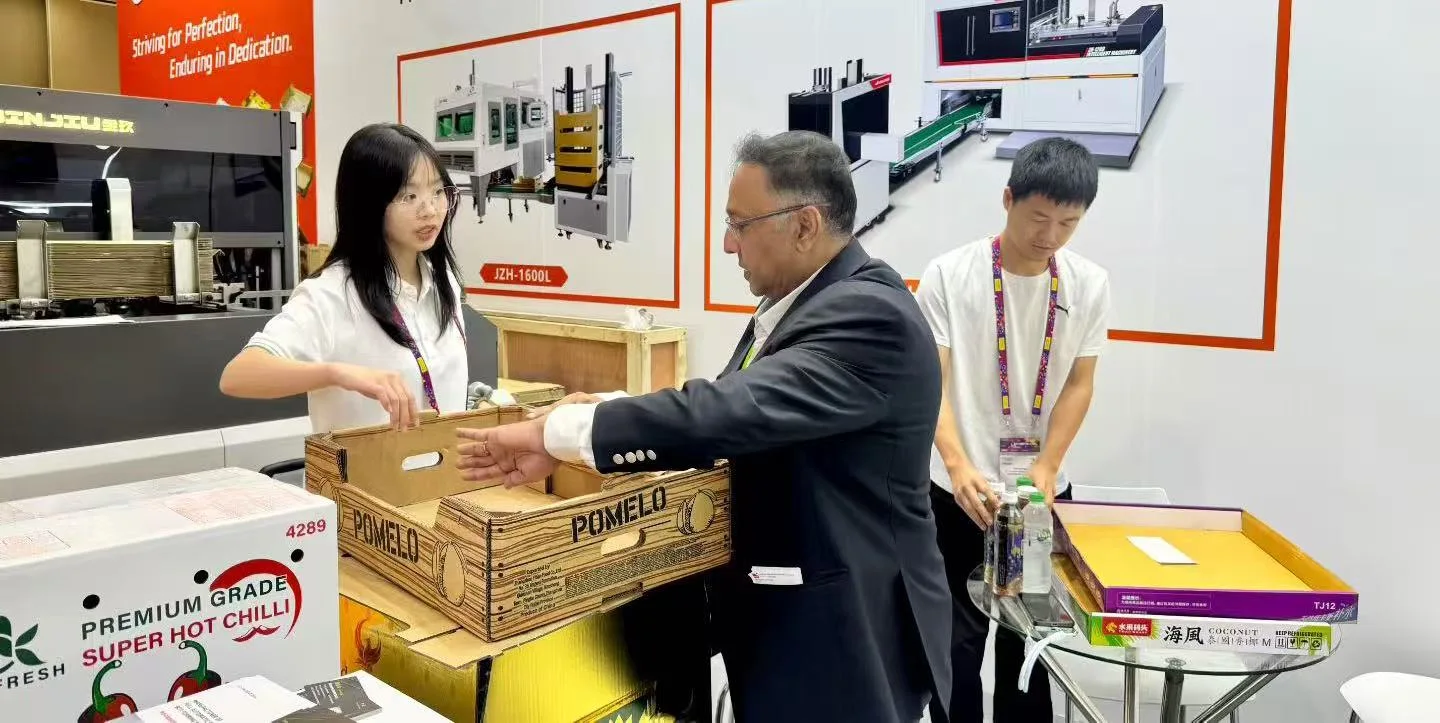A customer and exhibition staff examining a printed pomelo tray beside packaging equipment
