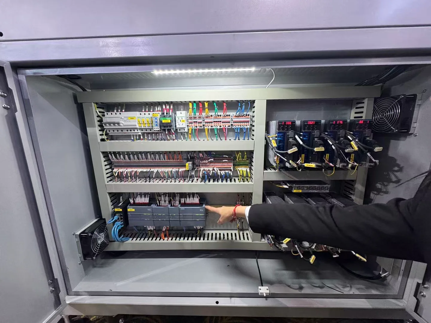 Open machine control cabinet showing labelled wiring, terminal rows, control modules and cooling fans