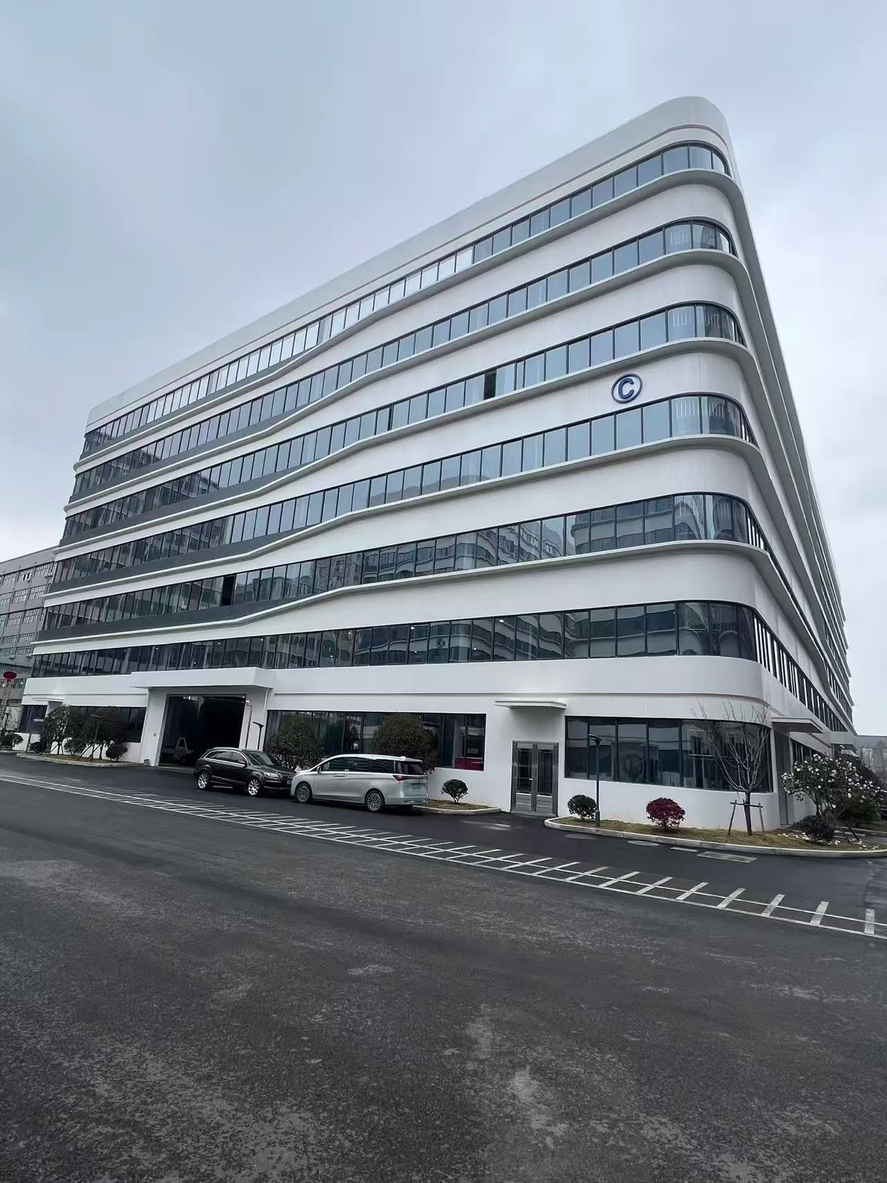 Exterior of the factory building with white walls, curved corners and rows of windows