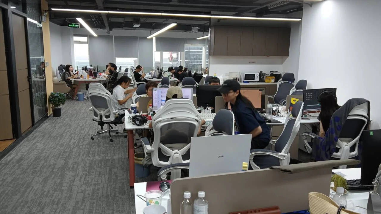 Xunding colleagues at desks in a shared office with windows and grey chairs