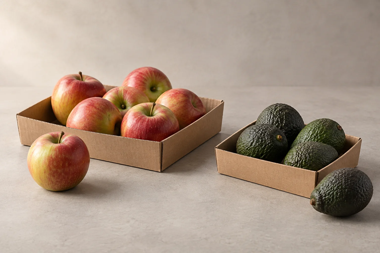 Two plain, shallow paperboard trays of different sizes with apples and avocados