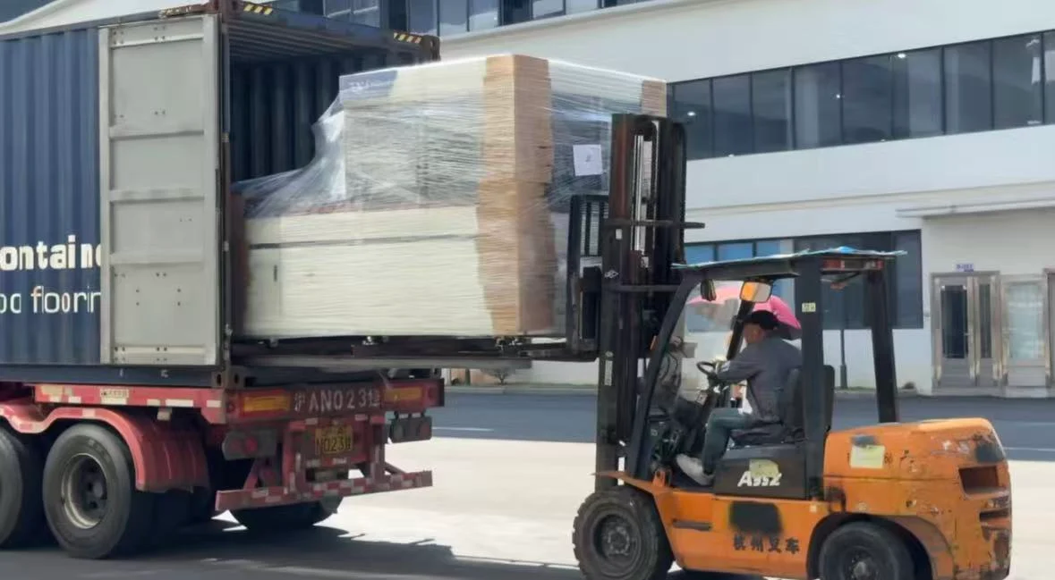 Forklift handling a wrapped box forming machine at the entrance of a shipping container
