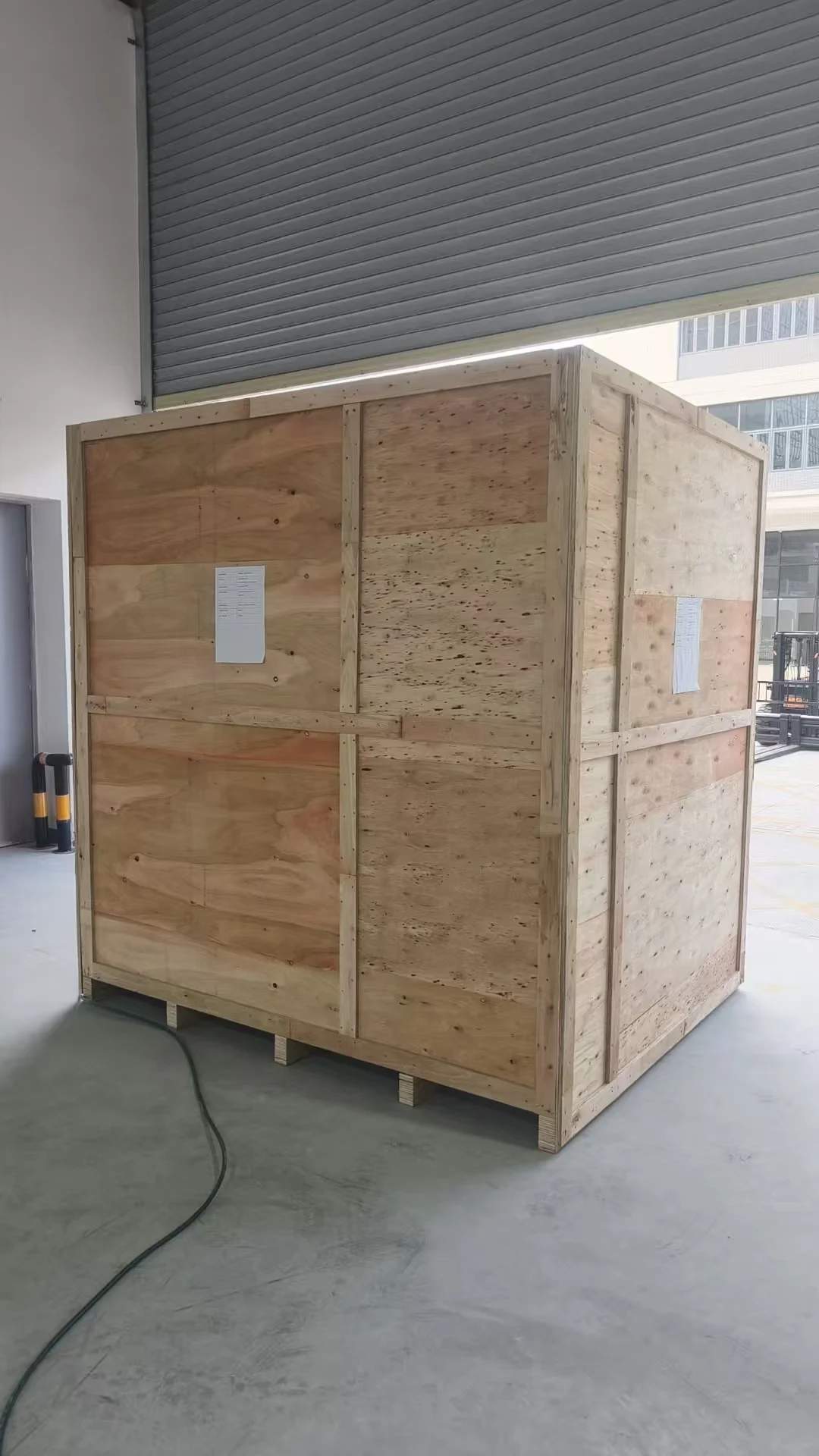 Closed wooden machinery shipping crate with packing labels and a timber base