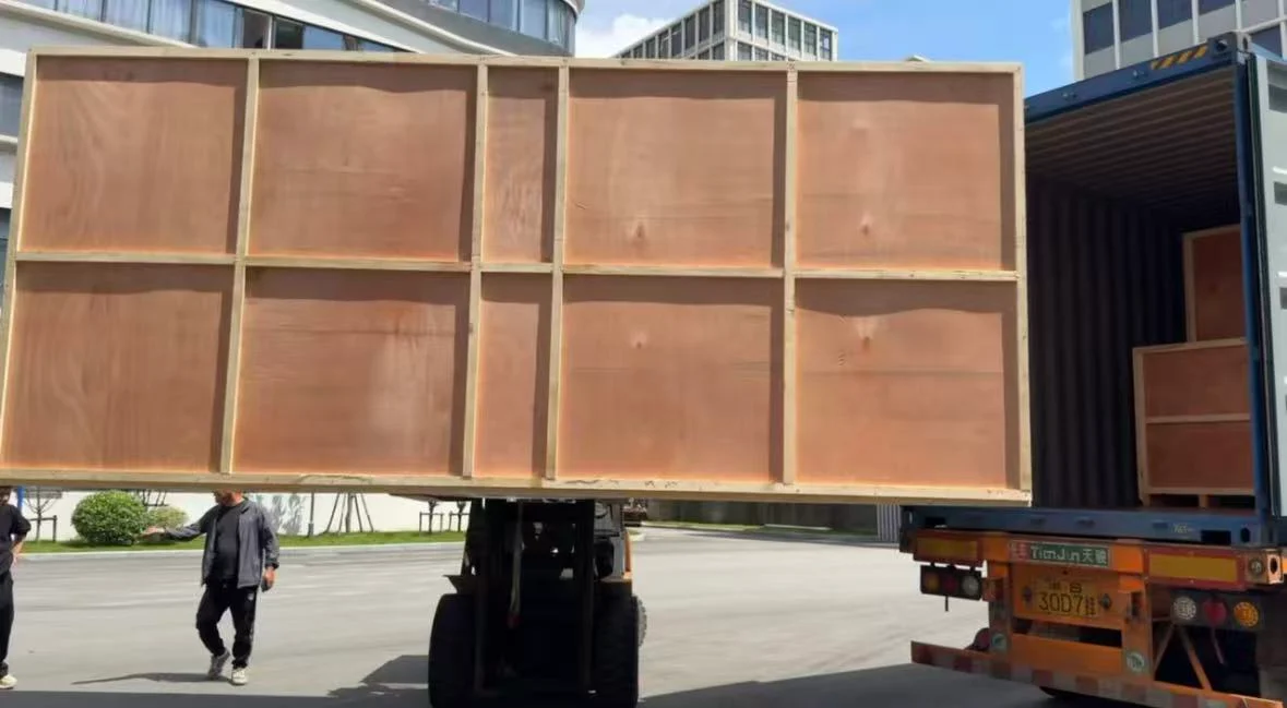 Large reinforced wooden machinery crate on a forklift beside an open shipping container