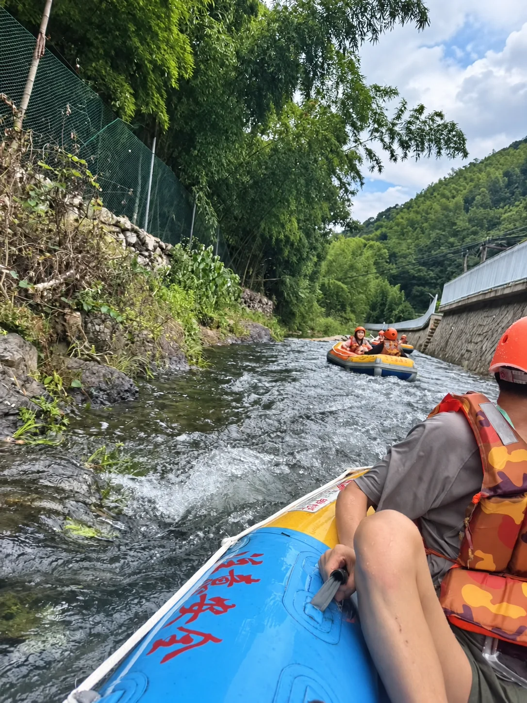 Xunding colleagues in inflatable rafts on a tree-lined waterway