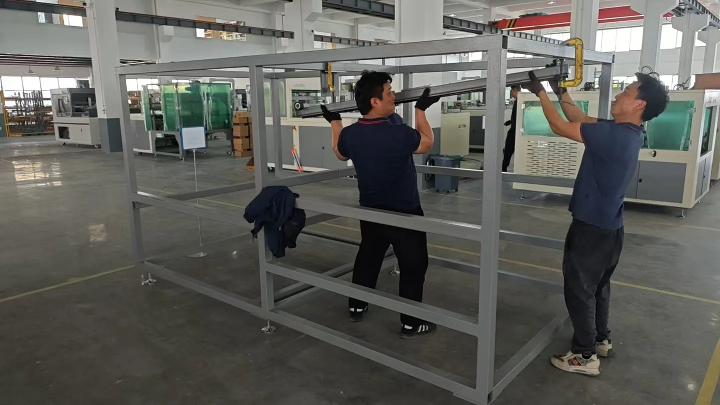 Two workers fitting a long component to a machine frame in the production workshop