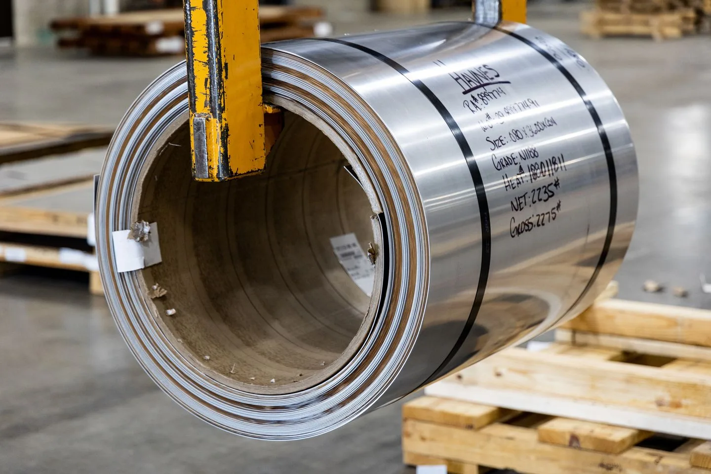 Close-up of a strapped metal coil with material identification markings in a warehouse