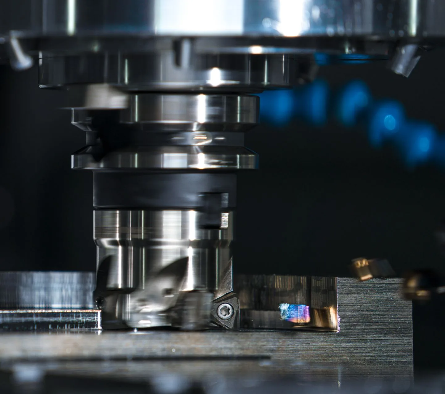 Close-up of a rotating milling cutter removing metal from a workpiece secured on a machine table